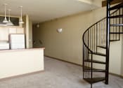 Thumbnail 10 of 30 - A spiral staircase in a room with a kitchen area.