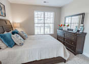 Thumbnail 10 of 22 - A bedroom with a large bed, a dresser, and a window with blinds.