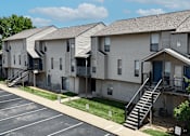 Thumbnail 24 of 31 - Apartment complex with a parking lot in front.