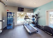 Thumbnail 18 of 31 - A gym with a treadmill, exercise ball, and a television.