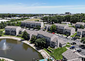 Thumbnail 26 of 31 - A large apartment complex with a fountain in the middle of a grassy area.