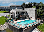 Thumbnail 22 of 31 - A small pool with a deck and a building in the background.