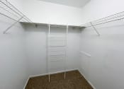 Thumbnail 8 of 21 - a spacious walk in closet in a bedroom with white walls