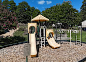 Thumbnail 10 of 16 - A playground with a yellow slide and a safety sign.