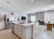 Thumbnail 33 of 93 - A modern kitchen with a refrigerator, sink, and dining table.at Copper Creek Apartments, Las Vegas Nevada