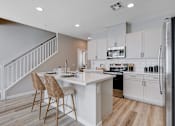 Thumbnail 6 of 93 - A kitchen with a white island and a refrigerator.at Copper Creek Apartments, Nevada