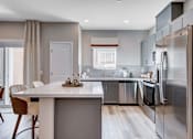 Thumbnail 51 of 93 - A modern kitchen with a dining table and chairs.at Copper Creek Apartments, Las Vegas, NV