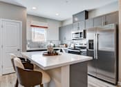 Thumbnail 48 of 93 - A modern kitchen with a white island and stainless steel appliances.at Copper Creek Apartments, Nevada