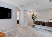 Thumbnail 68 of 93 - A living room with a grey carpet and a flat screen TV mounted on the wall.at Copper Creek Apartments, Las Vegas