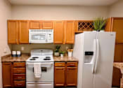 Thumbnail 5 of 20 - A kitchen with a white refrigerator and a white stove top oven.