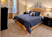 Thumbnail 13 of 20 - A bedroom with a bed, dresser, and ceiling fan.