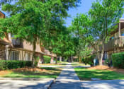 Thumbnail 11 of 20 - a sidewalk between two apartment buildings with green trees