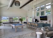 Thumbnail 7 of 42 - A billiard table is in the middle of a spacious room with a couch and a TV.