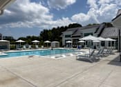 Thumbnail 2 of 42 - 1-Bedroom Luxury Apartments In Myrtle Beach, SC - Anchor Pointe - A Large Outdoor Community Pool With White In-Pool Loungers, Private Cabanas, And Striped Sun Umbrellas.