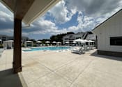 Thumbnail 4 of 42 - A large outdoor swimming pool with sun loungers and umbrellas.