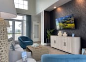 Thumbnail 14 of 42 - Myrtle Beach, SC, Luxury Apartments With In-Unit Washer and Dryer - Anchor Pointe - Living Room With Blue Armchairs, Coffee Table, Wall-Mounted Television, Media Console, and Glass Doors.