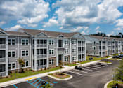 Thumbnail 32 of 42 - Apartment complex with a parking lot in front.