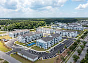 Thumbnail 38 of 42 - A large apartment complex with a parking lot in front.