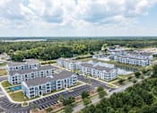 Thumbnail 21 of 42 - A large, modern apartment complex with a swimming pool and surrounded by greenery.