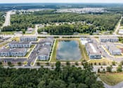 Thumbnail 29 of 42 - A bird's eye view of a residential area with a large pond in the center.