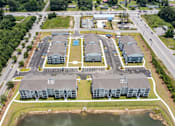 Thumbnail 23 of 42 - An aerial view of a large building complex with a parking lot and a body of water in front.