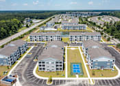 Thumbnail 27 of 42 - A large, modern apartment complex with a tennis court in the center.