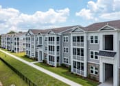 Thumbnail 42 of 42 - A row of modern townhouses with a sidewalk and green grass in front.