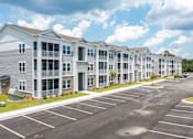 Thumbnail 34 of 42 - A parking lot in front of a row of apartment buildings.