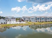 Thumbnail 36 of 42 - A large building complex is reflected in a body of water.