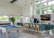 Thumbnail 13 of 42 - A pool table is in the middle of a room with a bar and a television.