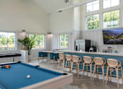 Thumbnail 11 of 42 - A pool table is in the middle of a room with a bar and a television.