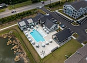 Thumbnail 19 of 42 - A large building with a pool in the middle of a grassy area.