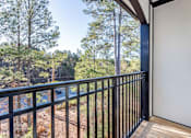 Thumbnail 49 of 52 - A balcony with a black railing overlooks a wooded area.