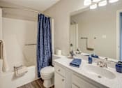 Thumbnail 11 of 15 - A bathroom with a white toilet, a white sink, and a blue shower curtain at River Ridge Apartments in Asheville, NC