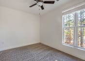 Thumbnail 40 of 52 - A room with a ceiling fan and a window overlooking a wooded area.