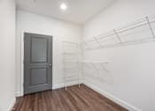 Thumbnail 48 of 54 - A room with a grey door and a white wall with a shelf on the wall.