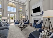 Thumbnail 12 of 19 - A clubhouse with a grey couch and blue chairs at Heights at New Garden apartments in Greensboro, NC.