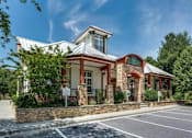 Thumbnail 20 of 20 - A building with a red roof and a stone wall in front.
