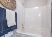 Thumbnail 28 of 32 - a bathroom with a white tub and a shower and blue towels