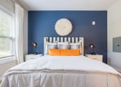 Thumbnail 19 of 32 - a bedroom with blue walls and a white bed with orange pillows