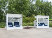 Thumbnail 7 of 32 - two white structures with blue chairs and a tree