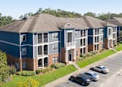 Thumbnail 10 of 14 - Apartment complex with a parking lot in front.