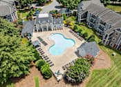 Thumbnail 18 of 19 - A large swimming pool surrounded by a patio and a small garden at Heights at New Garden apartments in Greensboro, NC.