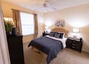 Thumbnail 10 of 20 - Dog-Friendly Apartments in Asheville, NC - Reserve at Asheville - Bedroom with Carpet Flooring, Bed, Nightstands, Table Lamps, Dresser, Wall Arts, Ceiling Fan, and Large Window with Coverings.