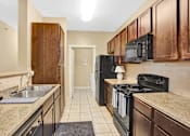 Thumbnail 5 of 14 - A kitchen with black appliances and wooden cabinets.