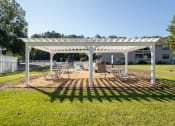 Thumbnail 26 of 35 - a white pergola with benches and tables in a park