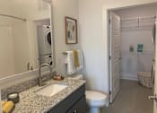 Thumbnail 8 of 19 - A bathroom with a single sink, white toilet, and large mirror hanging.