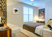 Thumbnail 7 of 19 - A bedroom with a bed, nightstand, and a picture on the wall.