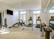 Thumbnail 13 of 19 - A well-equipped gym with various exercise machines and a flat-screen TV mounted on the wall.