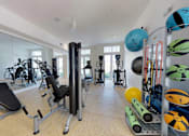 Thumbnail 10 of 19 - A gym with a variety of equipment including weights and exercise balls.